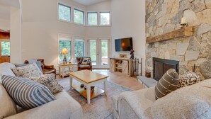 A spacious living room with a stone fireplace, a television, and a cozy seating area with a sofa and armchairs.
