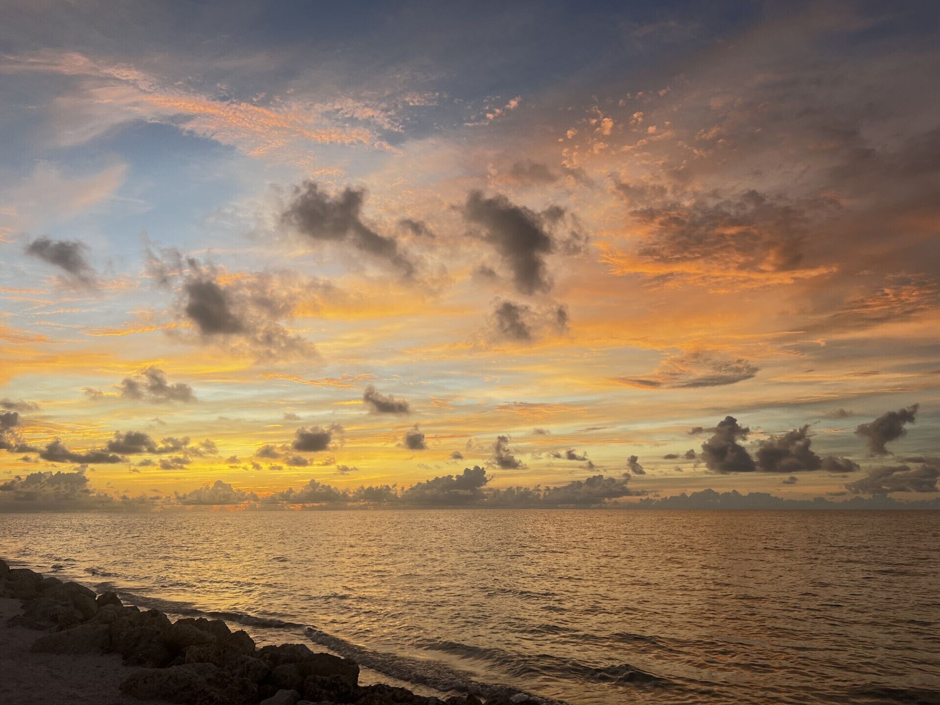A sunset over a calm sea with rocky coastline.