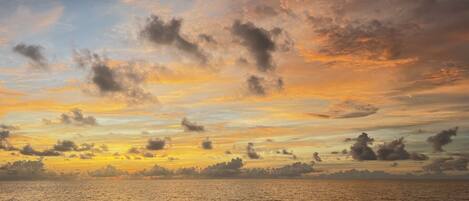A sunset over a calm sea with rocky coastline.