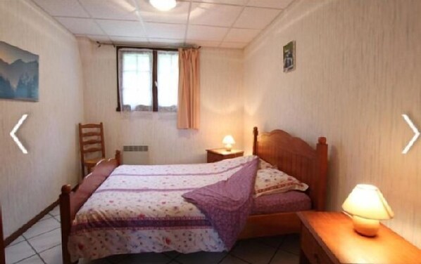 A small, neatly arranged bedroom with a single bed, a chair, a nightstand with a lamp, and a window with curtains. - Gîtes L' Ostau Barétous Pyrénées for 6 people (Aramits)