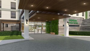 A modern hotel entrance with a wooden canopy, glass doors, and a stone facade. - Wyndham Garden Sacramento Airport Natomas (Sacramento)