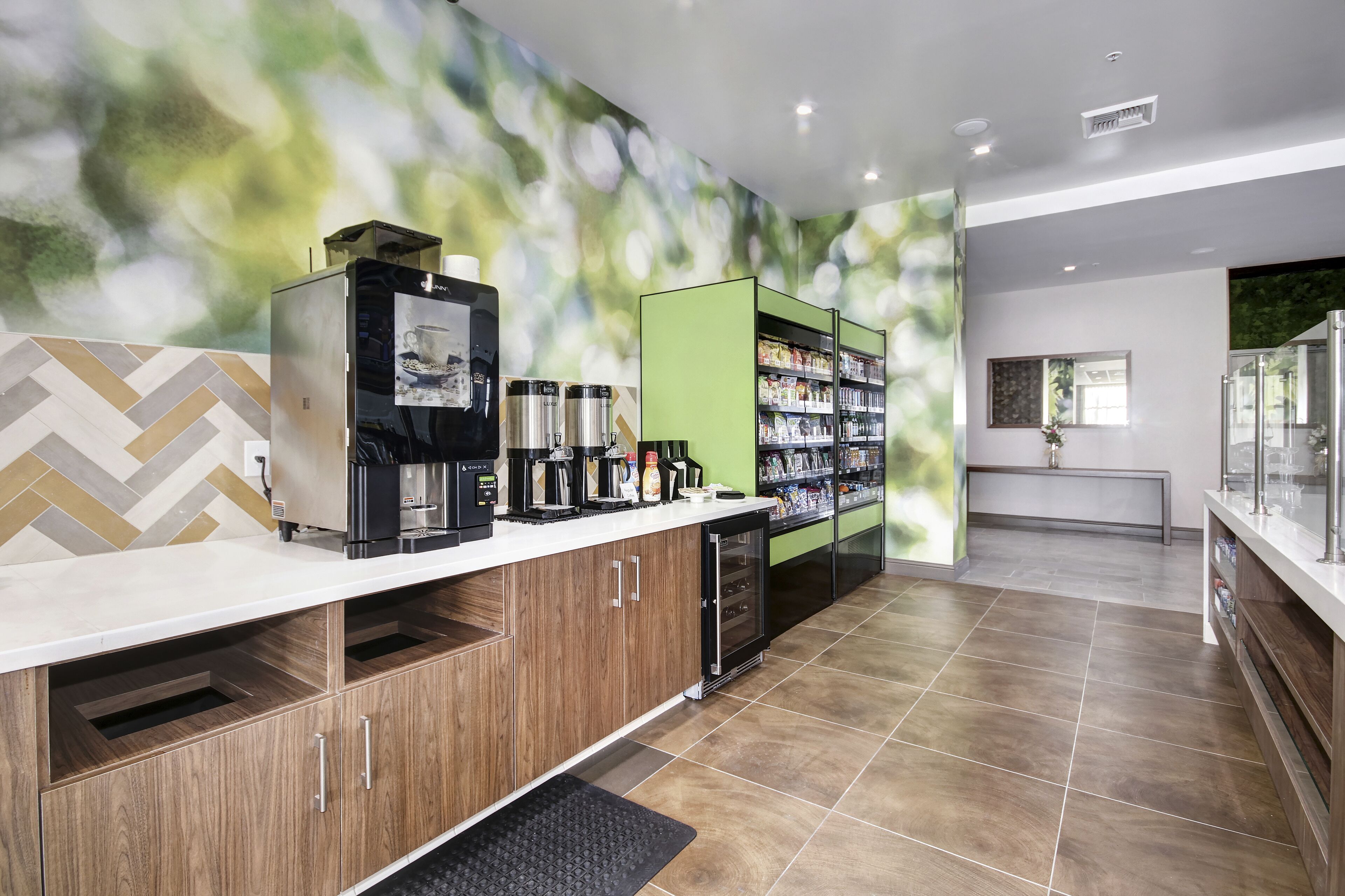 Una estación de café moderna con una cafetera, un refrigerador y una alacena para bebidas.