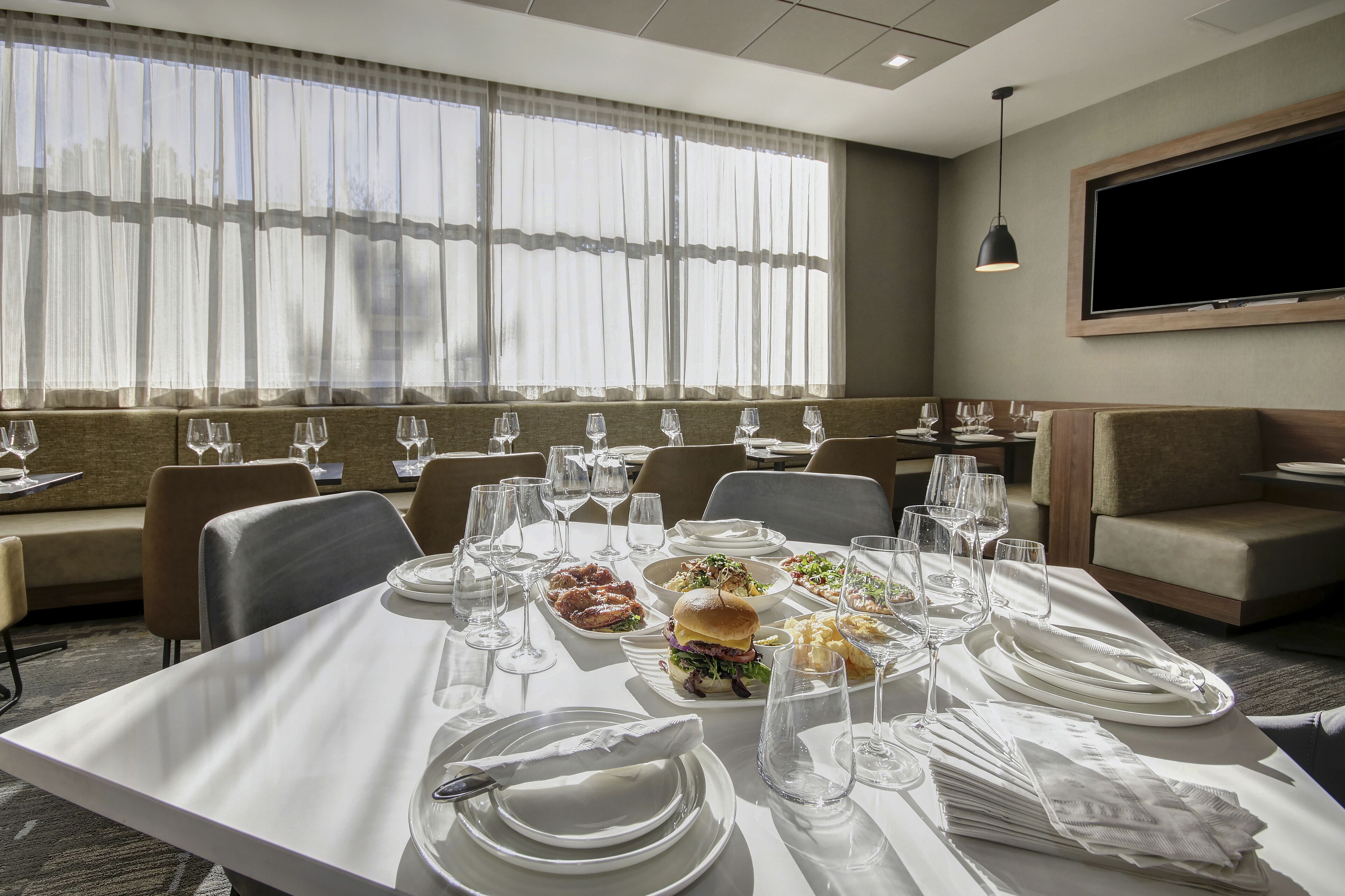 A hotel dining area with tables set for meals, including plates, glasses, and cutlery.
