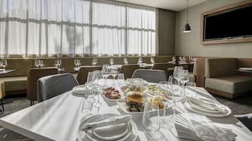 A hotel dining area with tables set for meals, including plates, glasses, and cutlery.