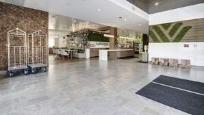 A spacious lobby with a modern design, featuring a reception desk, a seating area, and a large wall with a geometric pattern. - Wyndham Garden Sacramento Airport Natomas (Sacramento)
