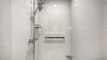A modern shower with a glass door, a handheld showerhead, and a wall-mounted control panel.