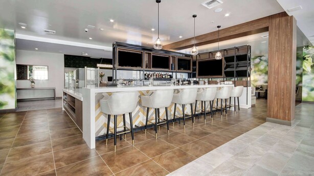 A modern kitchen with a central island, bar area with stools, and pendant lighting. - Wyndham Garden Sacramento Airport Natomas (Sacramento)