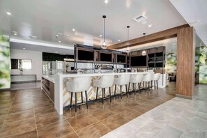A modern kitchen with a central island, bar area with stools, and pendant lighting. - Wyndham Garden Sacramento Airport Natomas (Sacramento)