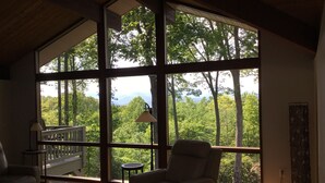 A spacious room with large windows offering a view of a forest and mountains. - 2.8 Acres of Mountain Magic.  Close to Everything.  (Pisgah Forest)