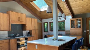 A modern kitchen with wooden cabinets, a central island, and pendant lighting. - 2.8 Acres of Mountain Magic.  Close to Everything.  (Pisgah Forest)