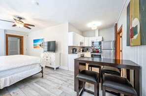 A bedroom with a bed, a TV, and a desk with chairs.