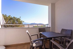 Un balcón con mesa y sillas, vistas a montañas y cielo despejado.
