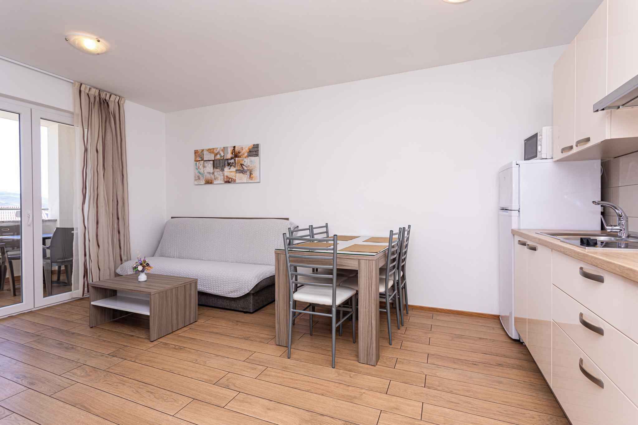 A compact living space with a kitchenette, a dining area with a table and chairs, a sofa, and a small coffee table.