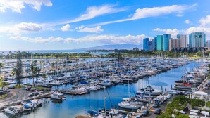 Ein Yachthafen voller Boote, im Hintergrund die Skyline einer Stadt und ein strahlend blauer Himmel.