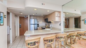 Una cocina moderna con una isla central, taburetes de bar y armarios de madera.