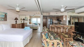 Una habitación de hotel con cama, sofá, televisión, zona de comedor y cocina.