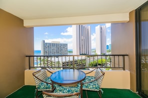 A balcony with a table and chairs, a view of a cityscape, and a building in the background.