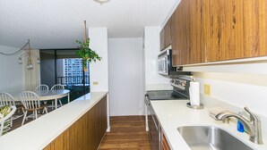 Une cuisine moderne avec des meubles en bois, un évier en acier inoxydable et un coin repas avec des chaises blanches.
