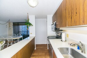A modern kitchen with wooden cabinets, a stainless steel sink, and a dining area with white chairs.