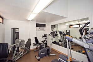 Une salle de sport équipée de matériel d’exercice, d’un miroir et d’une fenêtre.