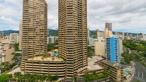 Two high-rise buildings with a curved facade, surrounded by other buildings and greenery. - Spacious Studio, Perfect Location In Wakiki, Located Near The Beach, Shopping (Honolulu)