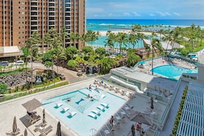 A resort with a pool area, palm trees, and a view of the beach.