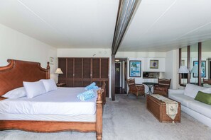 A hotel room with a bed, a sofa, a dining table, and a kitchenette.