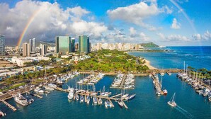 A marina with numerous boats docked, a city skyline with modern buildings, and a rainbow in the sky. - Perfect One-Bedroom Unit with an Ocean View! Ilikai Hotel, Great Location!  Going fast!  A++++ (Honolulu)