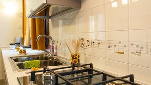 Una cocina moderna con electrodomésticos de acero inoxidable, encimera de vidrio y un salpicadero decorativo con notas musicales.