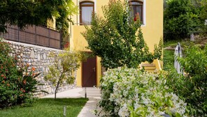 Un edificio amarillo con un muro de piedra y un camino que lleva a una puerta.