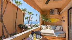 A balcony with a bed, a table with drinks, and a view of the beach. - New! Perfect Location with Great View of Ocean! (San José del Cabo)