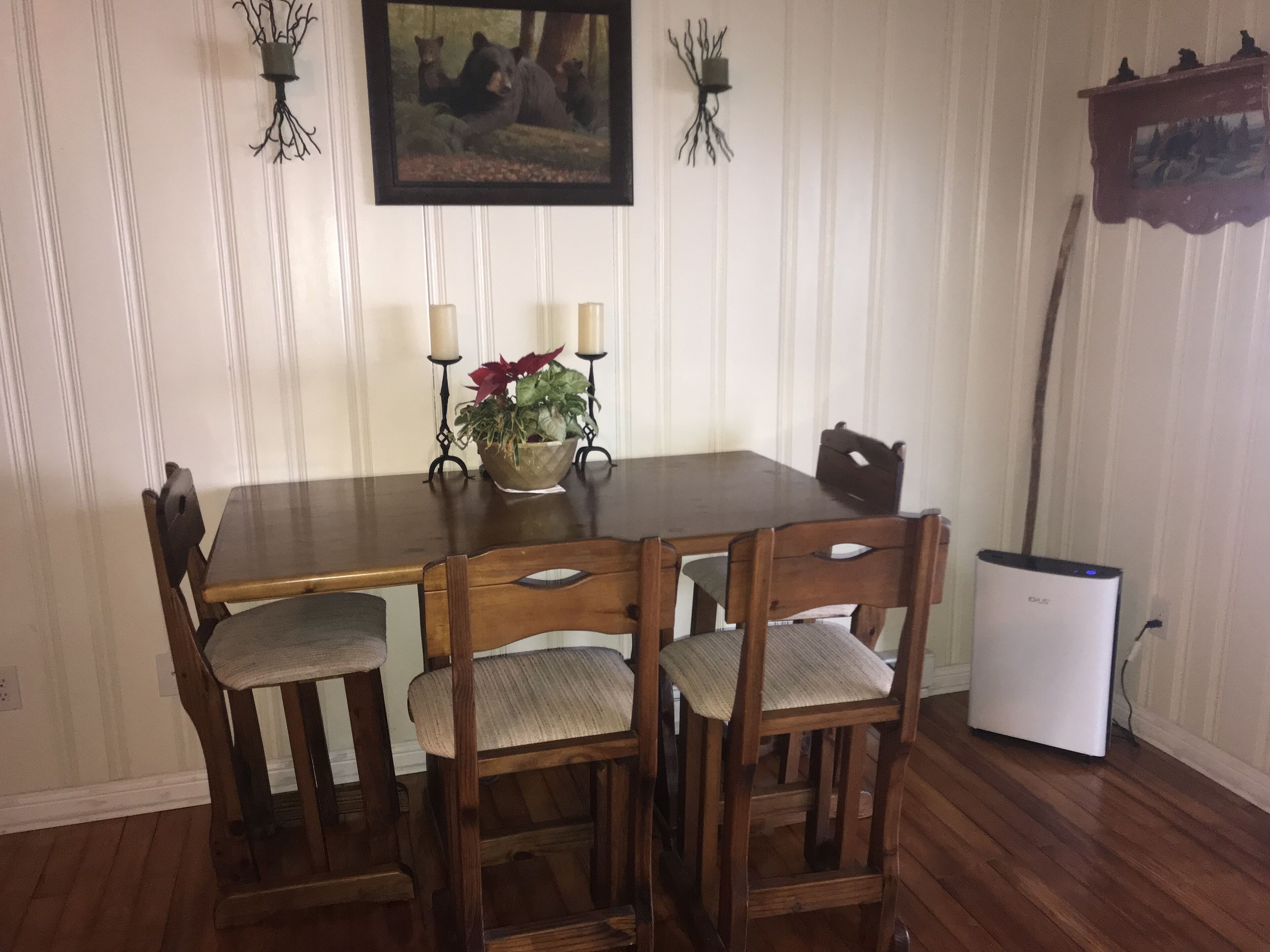 A dining table with four chairs, a small plant, and two candles.