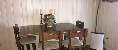 A dining table with four chairs, a small plant, and two candles.