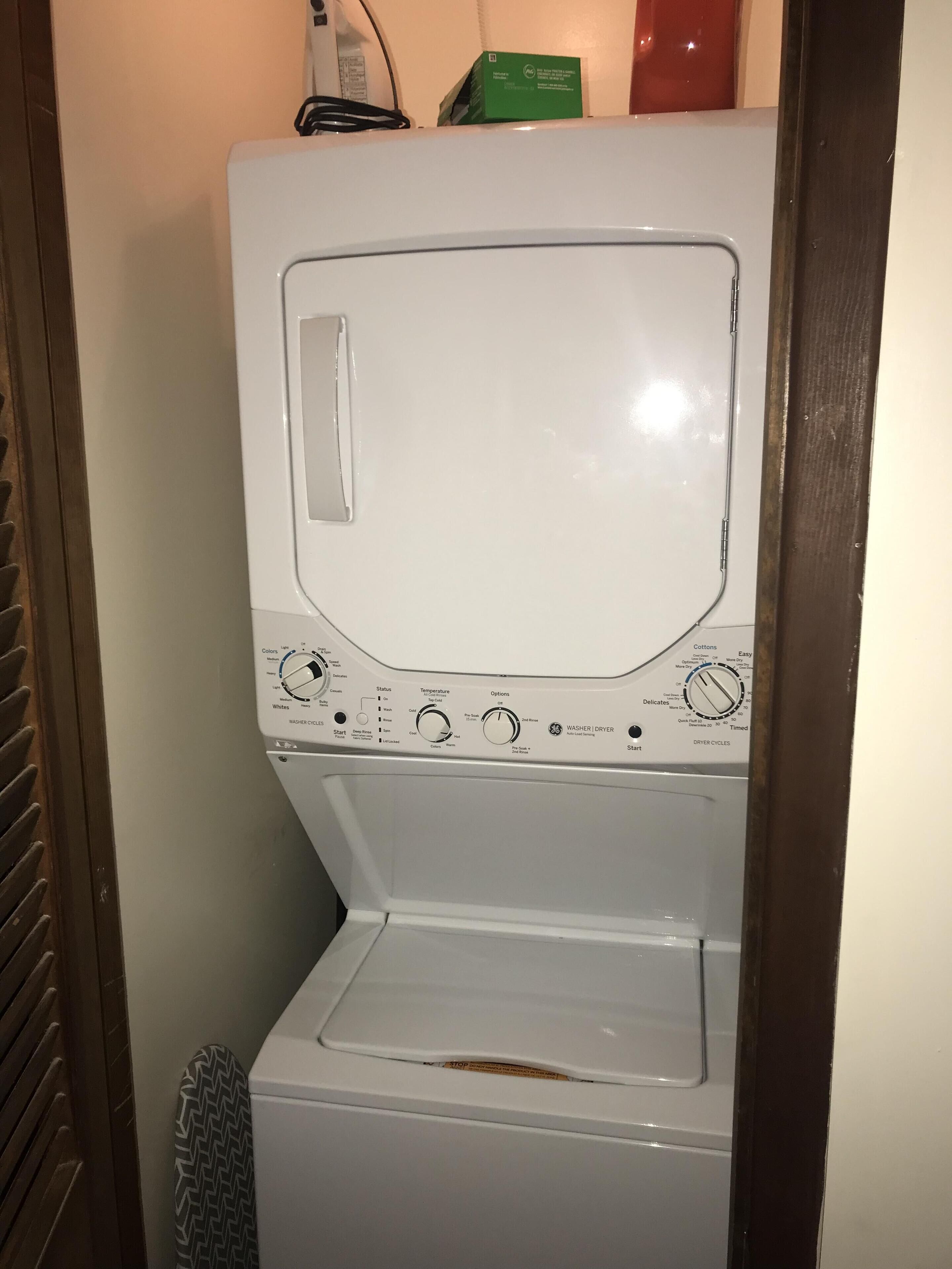 Eine weiße Waschmaschine mit Bedienelementen und einem kleinen Display, frontal abgebildet.