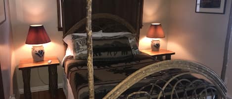 A four-poster bed with a rustic design, two bedside lamps, and patterned bedding.