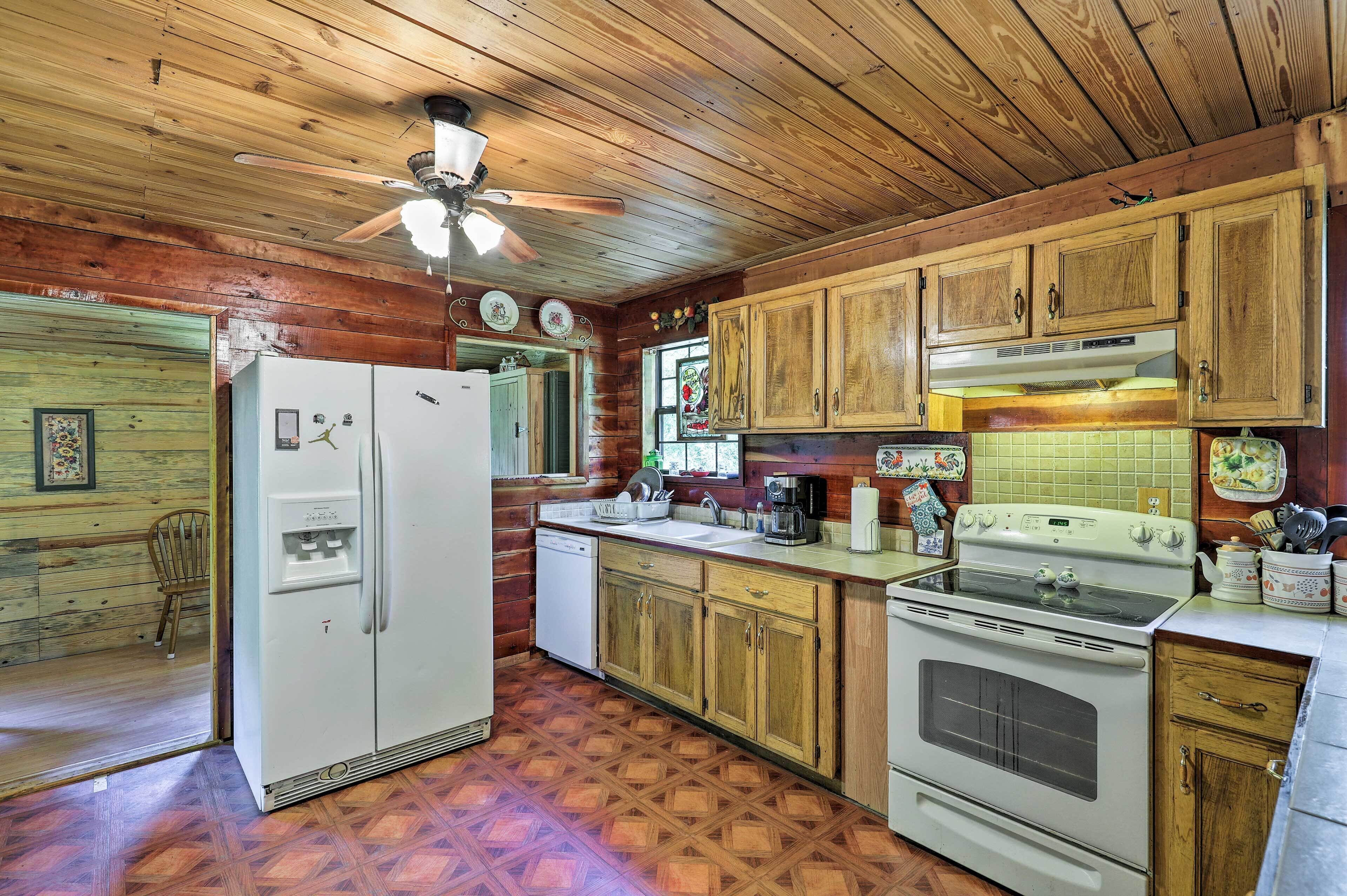 A kitchen with wooden cabinets, a white refrigerator, a stove, and a ceiling fan.