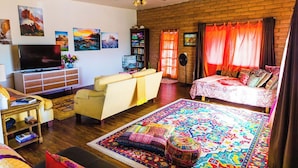 A cozy living room with a flat-screen TV, a sofa, a coffee table, and a patterned rug. - Local Artists Bohemian Loft (Sedona)
