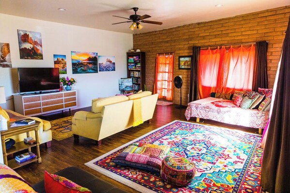 A cozy living room with a flat-screen TV, a sofa, a coffee table, and a patterned rug. - Local Artists Bohemian Loft (Sedona)