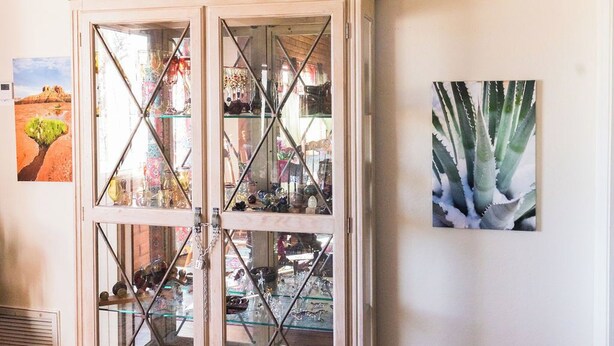 A room with a glass-fronted cabinet containing various items. - Local Artists Bohemian Loft (Sedona)