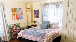 A bedroom with a large bed, a colorful rug, and artwork on the walls. - Local Artists Bohemian Loft (Sedona)