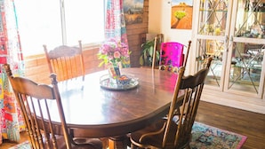 A dining area with a round table, wooden chairs, a colorful rug, and a window with curtains. - Local Artists Bohemian Loft (Sedona)