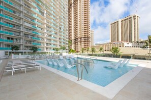 Un hotel con piscina, varios pisos y cielo despejado.