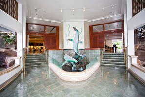 A lobby with a central fountain, a staircase, and a reception area.