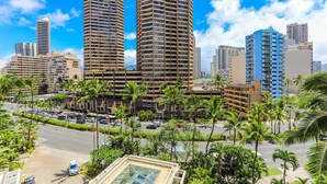 Un paisaje urbano con rascacielos, una calle concurrida y palmeras.