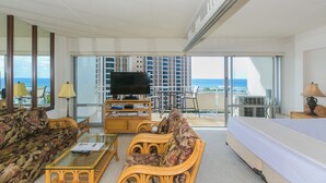 A spacious living room with a large TV, comfortable seating, and a balcony with a view of the ocean. - Ilikai Hotel One-bedroom Unit with am AMAZING view of the Duke Kahanamoku Lagoon and Waikiki Beach (Honolulu)