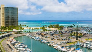 A marina with boats, a parking area, and a hotel in the background.