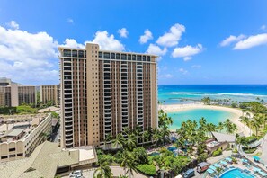 A high-rise hotel with a pool area, beach view, and palm trees. - Gorgeous Lagoon View At The Ilikai Hotel!  Firework view on Fridays! (Honolulu)