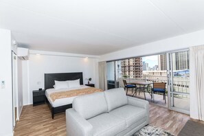 Ein modernes Hotelzimmer mit Bett, einer Sitzecke, einem Balkon mit Tisch und Stühlen und Blick auf die Stadtlandschaft.