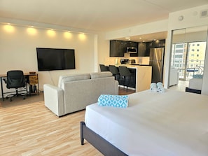 Une chambre d’hôtel comprenant un lit, un canapé, un bureau avec une chaise, une télévision et une kitchenette.