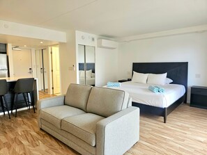 Hotellihuone, jossa on sänky, sohva, työpöytä ja peili.